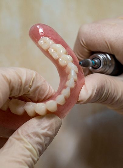 Lab technician filing dentures