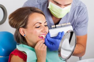Woman looking into mirror trying on veneers.